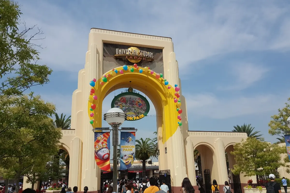 The cream-coloured entrance arch of Universal Studios Japan with a yellow garland of coloured beads and banners hanging beneath it